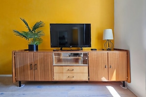 A wooden cabinet with a television on top, a potted plant, and a lamp.