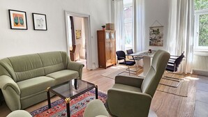A living room with a sofa, armchairs, a coffee table, and a dining area with a table and chairs. - Yellow Palm - 60m2 - cozy, central with a green view (Wien)