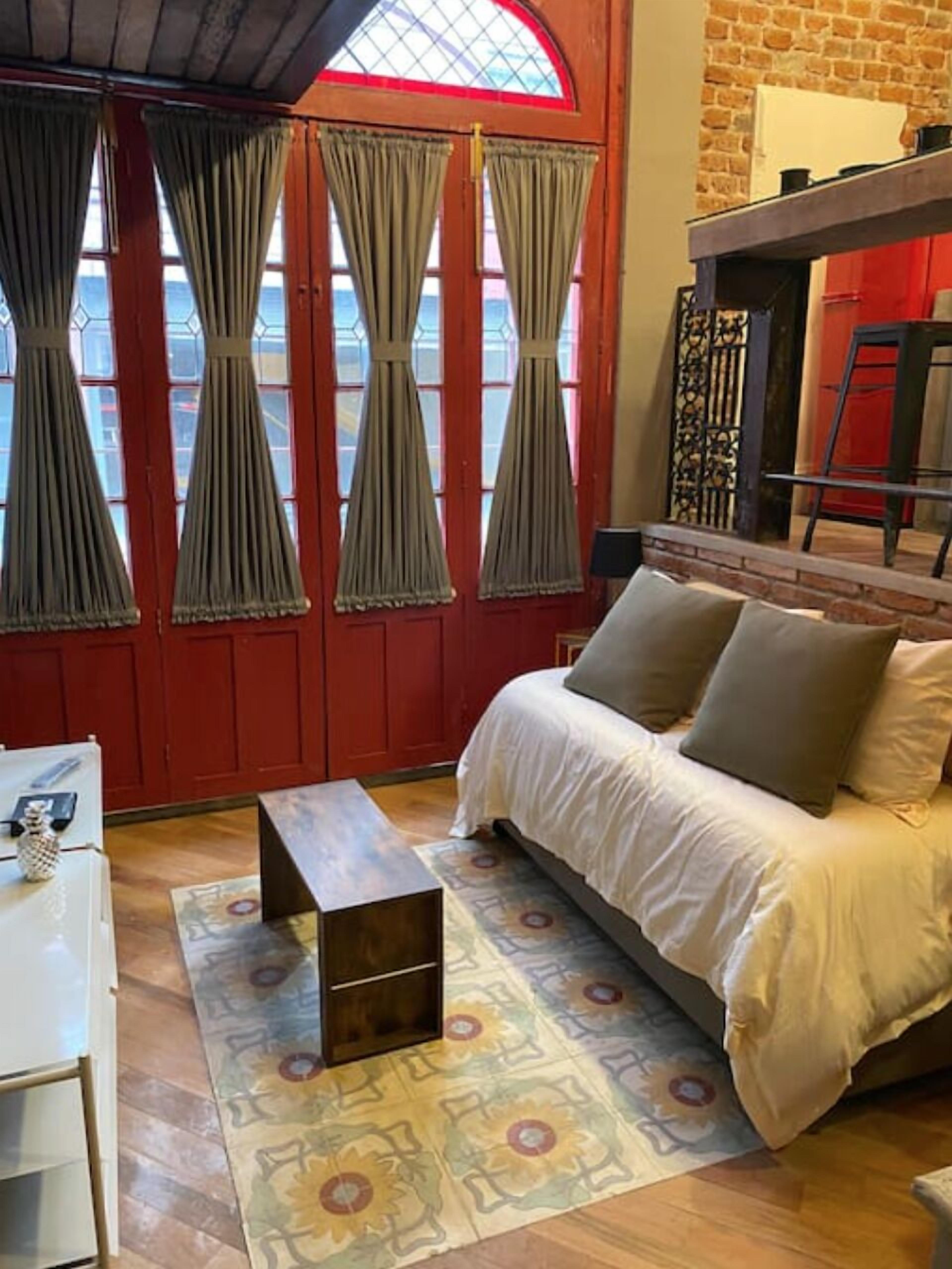 Une chambre confortable avec un lit, une petite table et une fenêtre avec des rideaux.