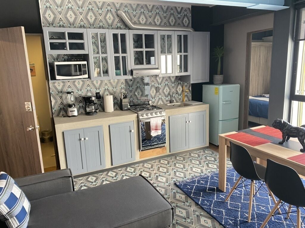 Une cuisine compacte équipée d’un four à micro-ondes, d’une cuisinière et d’un évier. Un coin repas avec une table et des chaises est également disponible.
