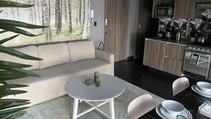 A modern living room with a sofa, a round table, and a dining area with chairs and a table set for a meal. - Hotel Puerta Roja Reforma  (Mexico City)