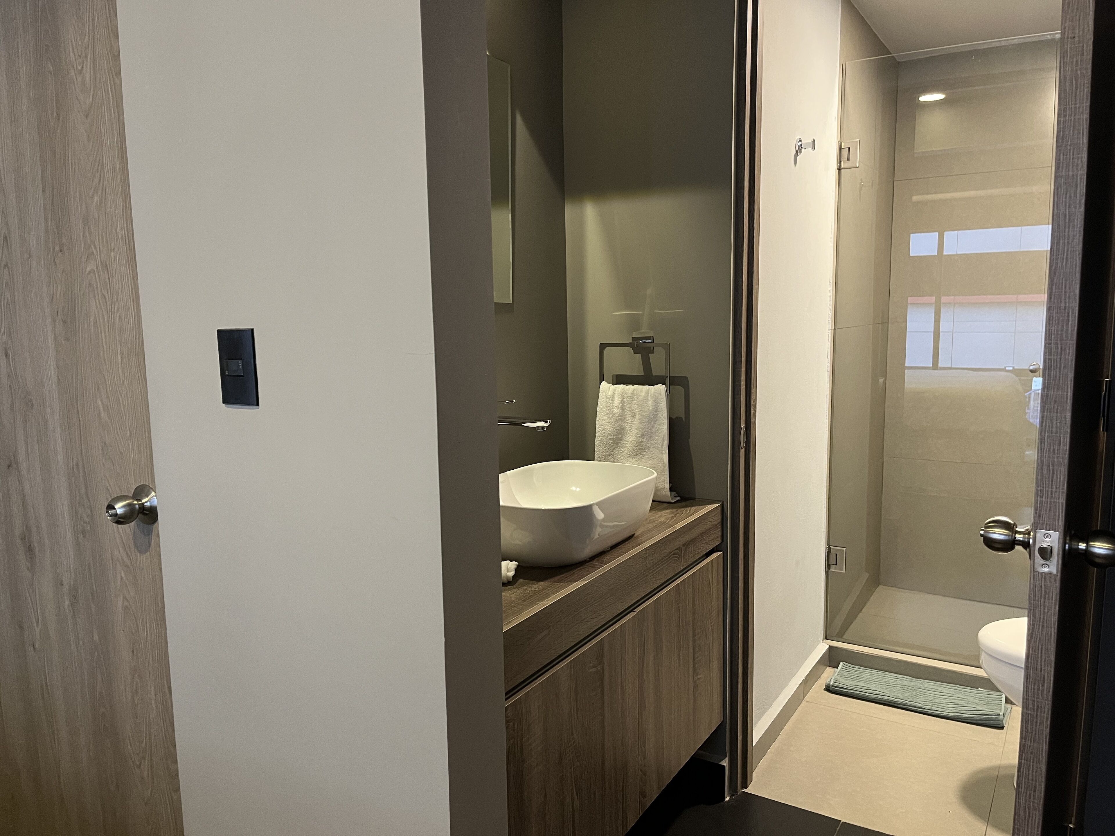 A modern bathroom with a large white sink, a mirror, and a towel hanging on a rack.