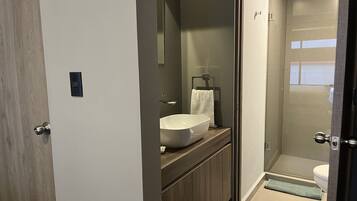 A modern bathroom with a large white sink, a mirror, and a towel hanging on a rack.