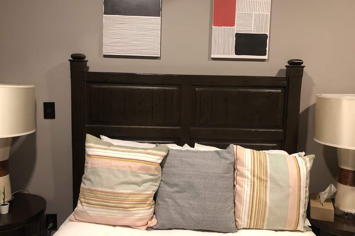 A bed with multiple pillows and two bedside tables with lamps.