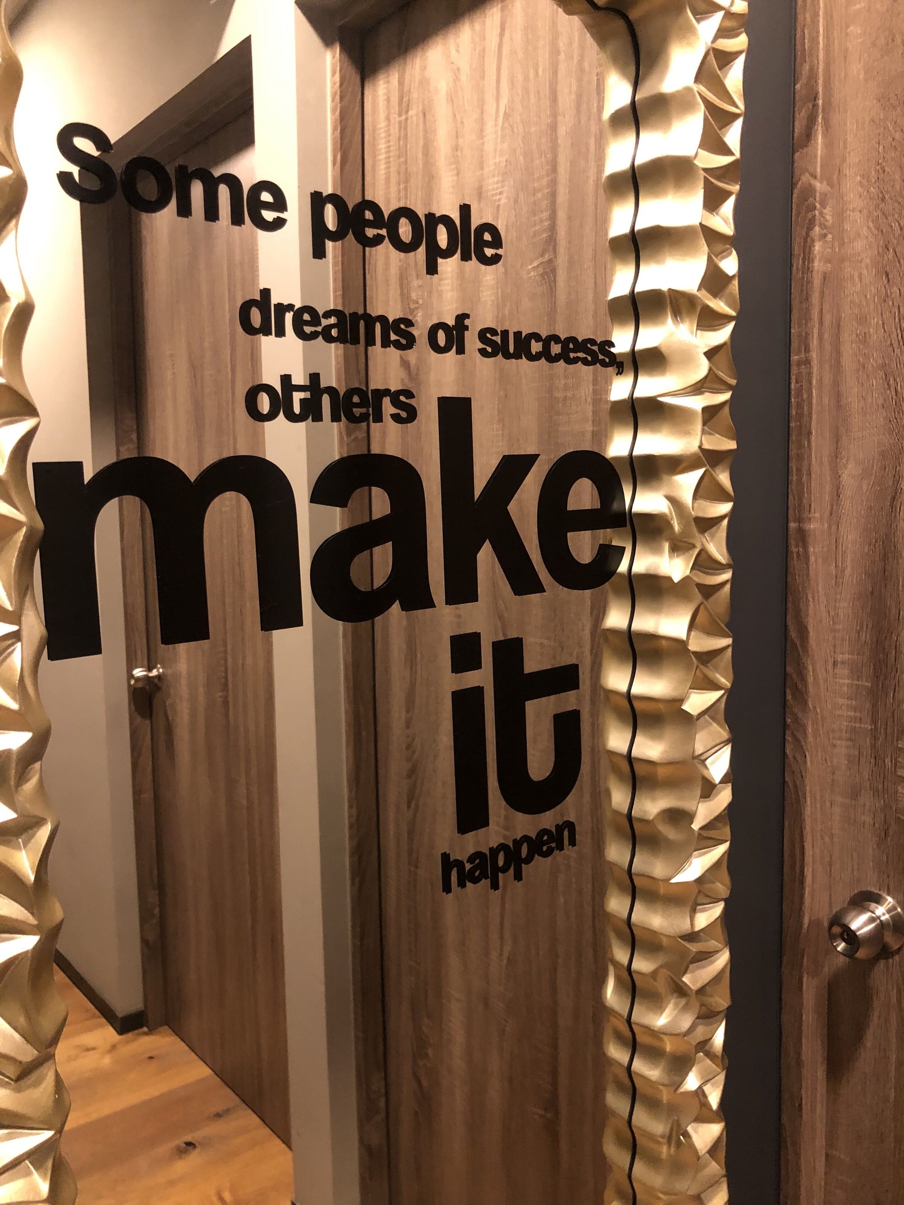 Una porta in legno con una frase motivazionale e una rifinitura decorativa a frange.