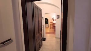 A hallway with a dark wooden door, white walls, and a tiled floor.