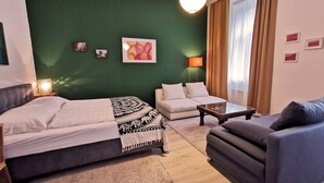 A room with a bed, a sofa, a coffee table, and a lamp.