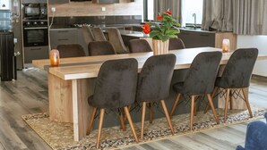 Una cocina moderna con una isla de madera, sillas oscuras y un jarrón con flores.