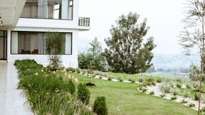 Un edificio moderno de dos pisos con un jardín cuidado y vistas a un cuerpo de agua.