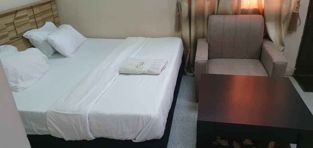 A hotel room with a bed, a chair, and a small table.