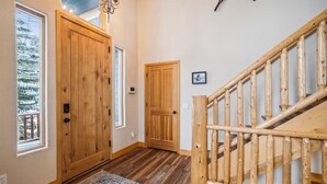 A wooden staircase with a handrail, a wooden door, and a small window with a view of snow-covered trees. - Frisco Ski Home, New Hot Tub, Fireplace, Near 3 Resorts, Sleeps 10 (Frisco)
