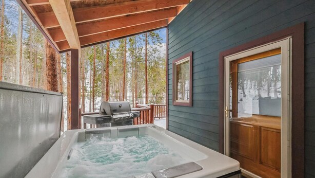 A hot tub in a covered outdoor area with a wooden deck and a view of trees. - Frisco Ski Home, New Hot Tub, Fireplace, Near 3 Resorts, Sleeps 10 (Frisco)