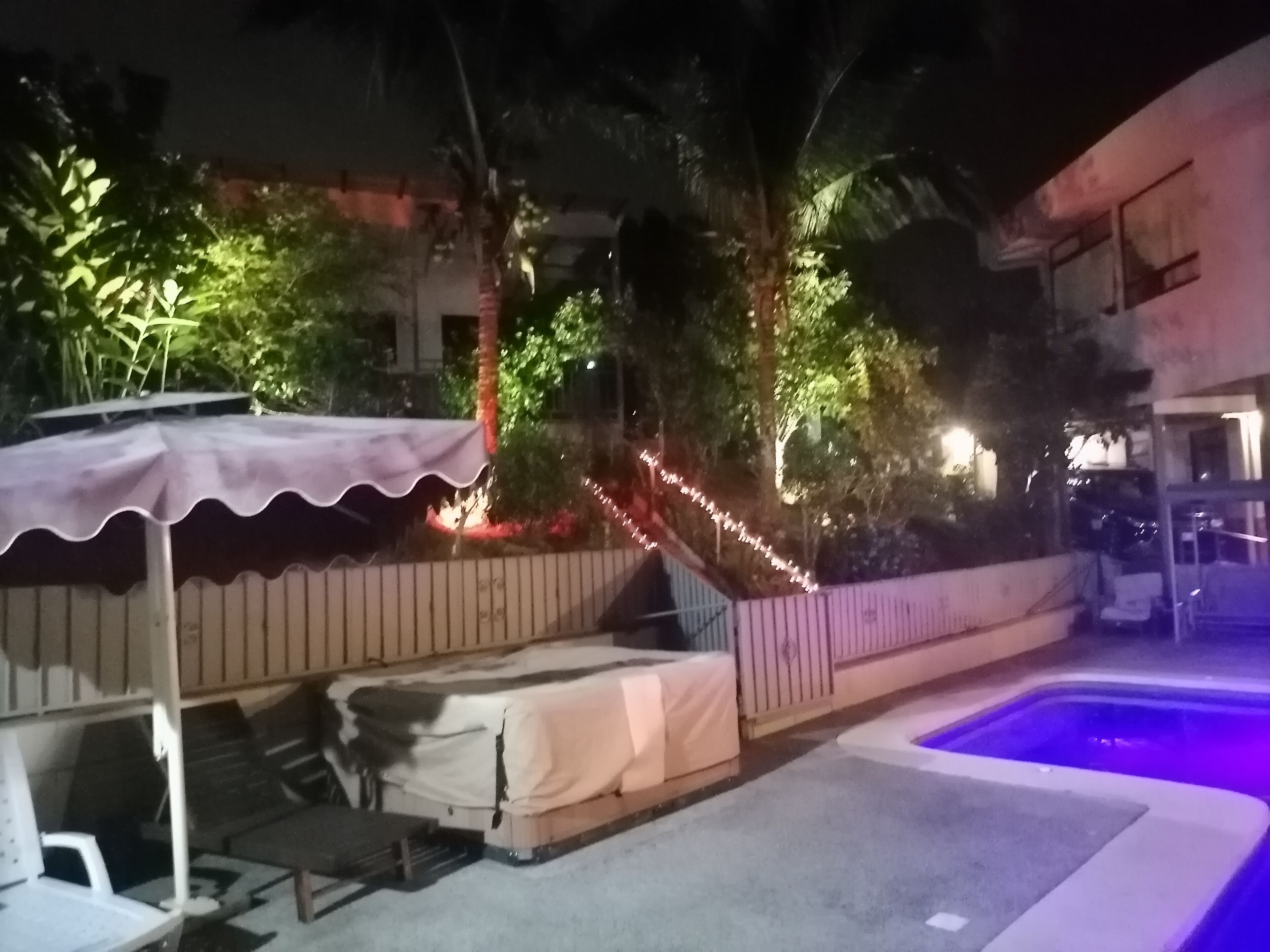 Un área de piscina con una zona de estar cubierta y una escalera que sube a un edificio.