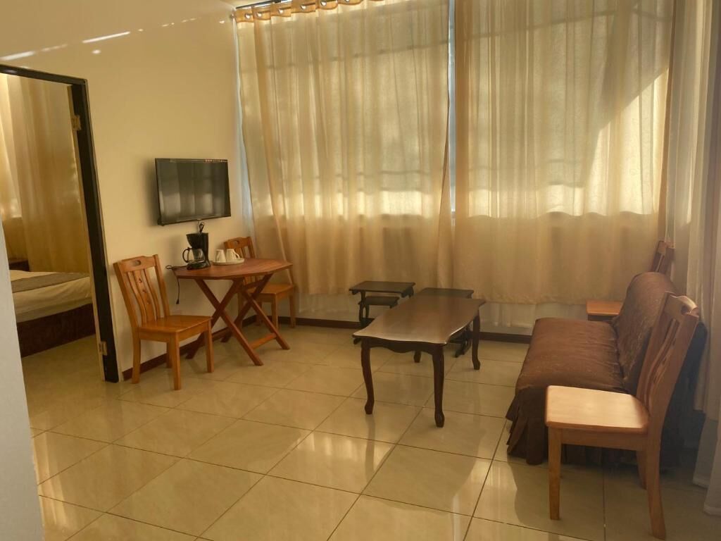 A living room with a sofa, two chairs, a coffee table, a TV, and a dining table.