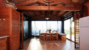 L’intérieur d’une cabane en bois comprend un coin repas, des meubles de rangement en bois et un sol carrelé.
