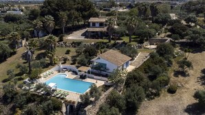 Une villa avec piscine, entourée d ’arbres et située dans un paysage vallonné.