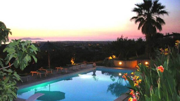 Une piscine avec des chaises longues et une vue sur le coucher de soleil.