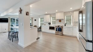 Una cocina moderna con armarios blancos, un refrigerador de acero inoxidable y un horno empotrado.