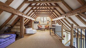 Ein Dachzimmer mit freiliegenden Holzbalken, einem Sofa, einem Sessel und einem kleinen Tisch.