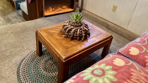 Una sala de estar acogedora con una mesa de centro de madera, una pequeña planta en maceta, un sofá y una chimenea.