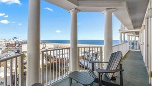 Un balcon orné de colonnes blanches, une vue sur l’océan et, au loin, une rangée de maisons de plage.