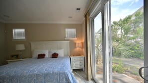 A bedroom with a large bed, two bedside tables, a window with blinds, and a view of the outdoors. - Beautiful House-Owner's Secrete Treasure, Private Backyard, 3 min to the Beach! (Myrtle Beach)