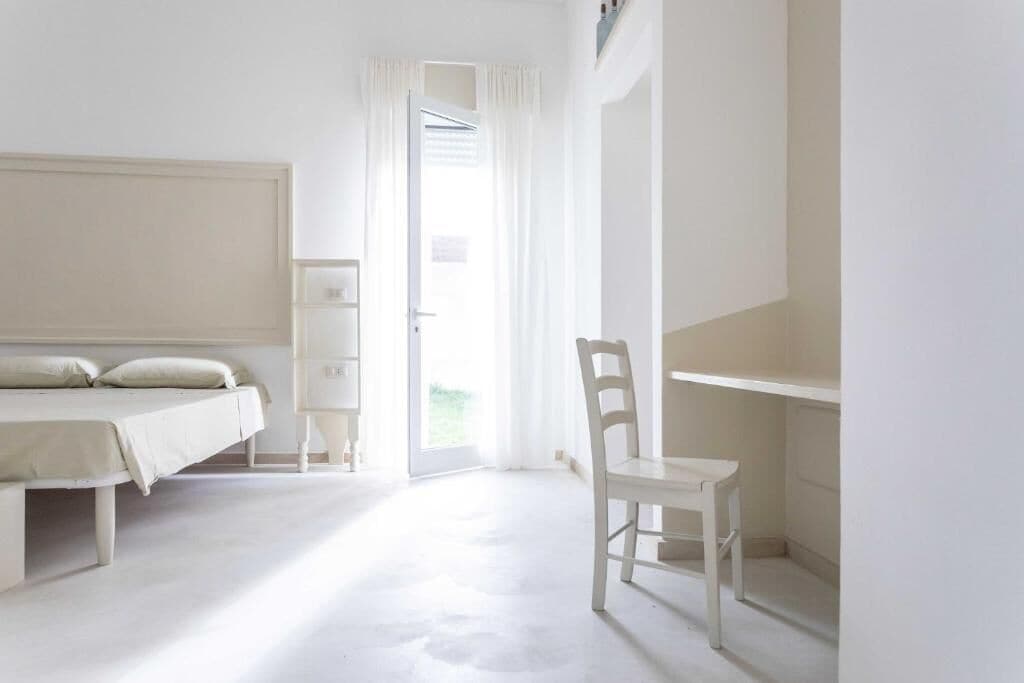 A minimalist bedroom with a bed, a chair, and a desk.
