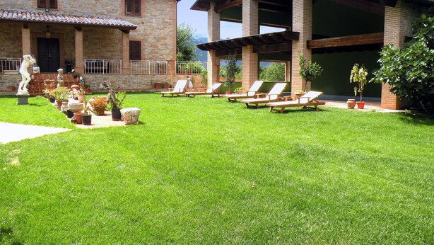 A courtyard with a stone building, a modern structure, and outdoor seating.
