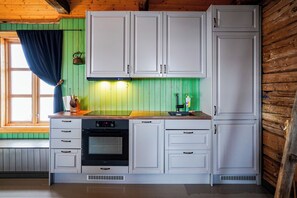 Una cocina con armarios blancos, una estufa y una ventana con cortina.