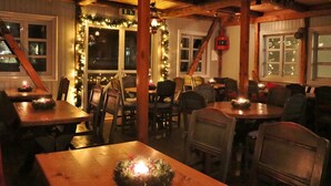 A cozy restaurant interior with wooden tables and chairs, festive decorations, and a warm ambiance.