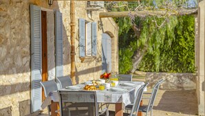 A table set for breakfast with a view of a stone building and greenery. - Finca Can Castell 1 for 6 with swimming pool, Bbq, free WiFi (Alcúdia)