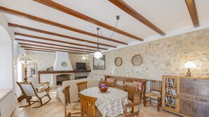 A dining area with wooden furniture, a stone wall, and a fireplace. - Finca Can Castell 1 for 6 with swimming pool, Bbq, free WiFi (Alcúdia)