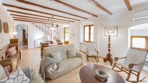 A spacious living room with a sofa, chairs, a coffee table, and a dining area with a table and chairs. - Finca Can Castell 1 for 6 with swimming pool, Bbq, free WiFi (Alcúdia)
