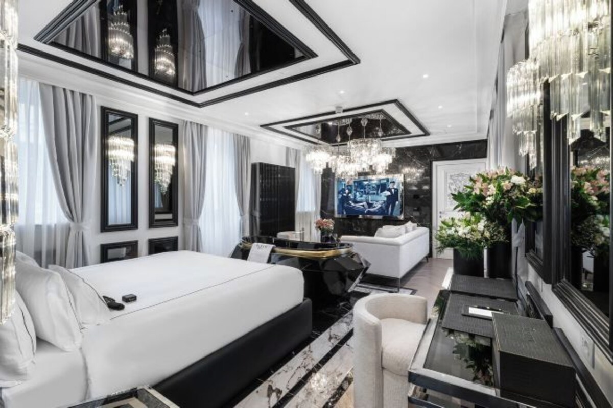 Une chambre d’hôtel moderne dotée d’un grand lit, d’un coin salon avec un canapé et une petite table, ainsi que d’un grand miroir.