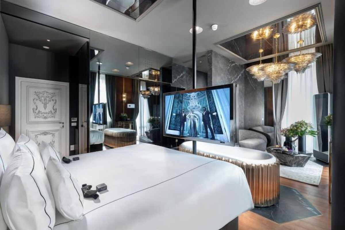 A modern hotel room with a large bed, a television, and a mirror.