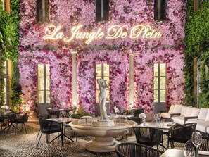 A restaurant with a floral wall, a fountain, and outdoor seating. - The Plein Hotel - Small Luxury Hotels of the World (Milan)