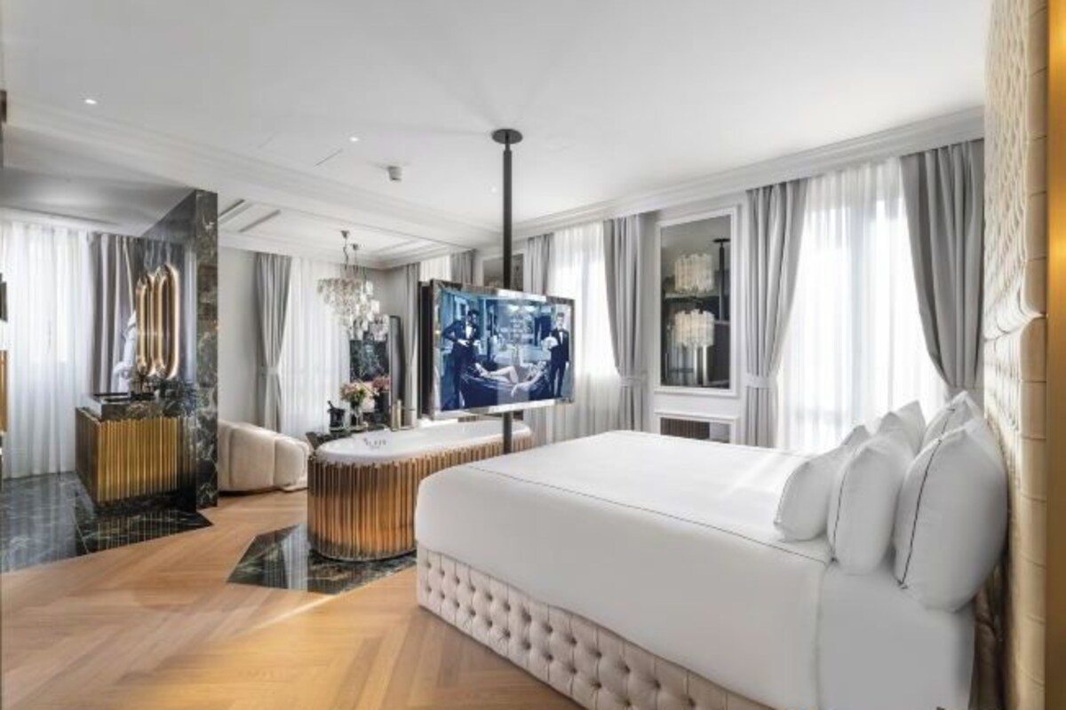Une chambre d’hôtel moderne dotée d’un grand lit, d’une télévision et d’un coin salon avec une table et des chaises.