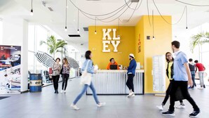 A modern indoor space with a yellow reception area, a counter, and a few people walking. - Résidence Kley Toulouse (Toulouse)