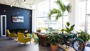 A modern lounge area with a leather couch, yellow chairs, a television, and a vintage motorcycle. - Résidence Kley Toulouse (Toulouse)
