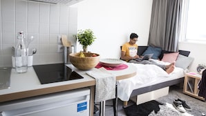 A modern hotel room with a bed, a small desk with a laptop, a bowl of fruit, and a potted plant. - Résidence Kley Toulouse (Toulouse)