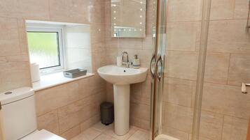 Een badkamer met toilet, wastafel en douche.