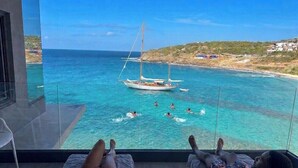 A balcony with a view of the sea, a sailboat, and people swimming. - Condostmaarten panoramic appartment (Adults Only) (Sint Maarten)