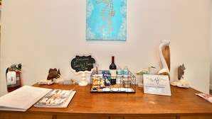 Un comptoir d’accueil avec une pancarte de bienvenue, un panneau indiquant la présence d’une connexion Wi-Fi, des collations et une bouteille de vin.