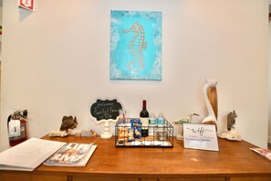 A reception desk with a welcome sign, a WiFi sign, snacks, and a wine bottle.
