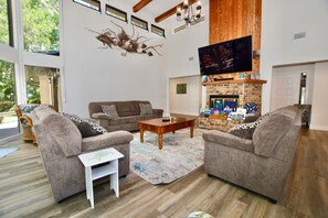 A living room with two sofas, a coffee table, a fireplace, and a TV mounted on the wall.