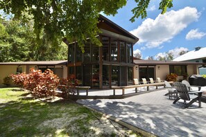 A modern building with large windows, a patio with outdoor seating, and a well-maintained garden.