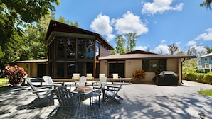 Une maison moderne à deux étages dotée d’un patio aménagé avec des meubles d’extérieur et un foyer.
