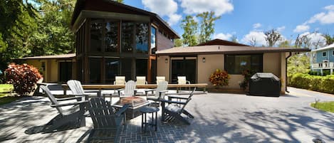 A modern two-story house with a patio area featuring outdoor furniture and a fire pit.