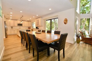A spacious kitchen with white cabinets, a large island, and a dining area with a wooden table and chairs.