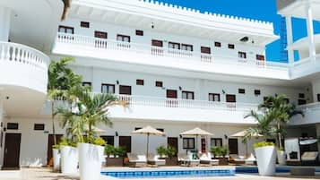 A multi-story hotel with a central courtyard, outdoor seating, and a pool.